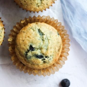 dairy free blueberry muffin with the paper liner unwrapped from it.