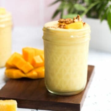 pineapple mango smoothie in a mason jar topped with fruit and granola.