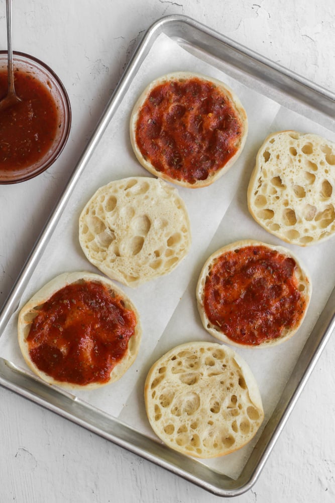 toasted English muffins with pizza sauce on half of them.