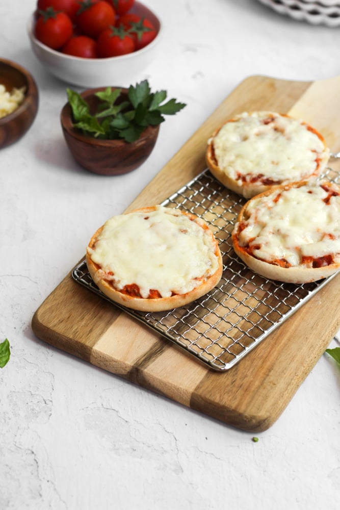 mini pizzas in the air fryer on wood cutting board.