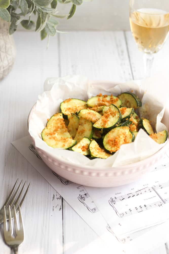 air fryer zucchini in a pink bowl with a gluten free bread crumb.