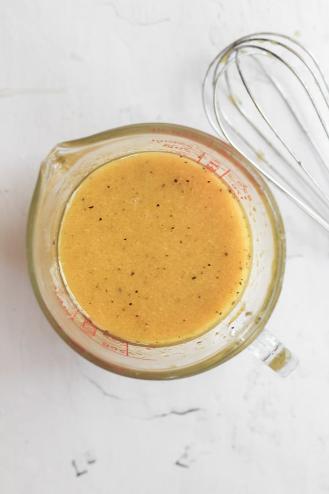 apple cider vinaigrette in a small measuring cup. 