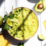 guacamole recipe with no onion in a white bowl with window pane shadows crossing over the center.