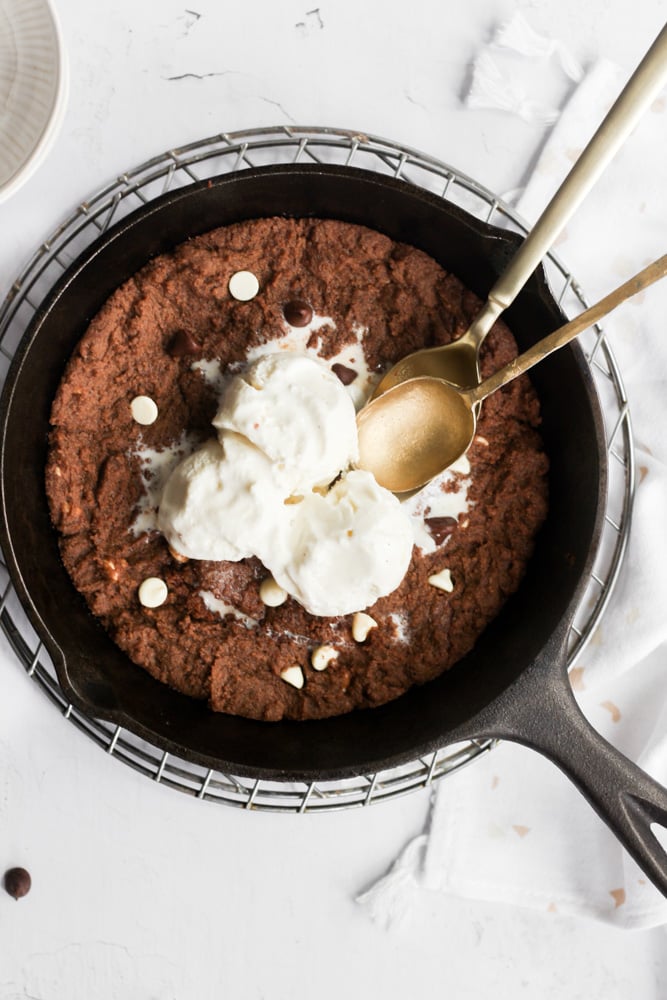 mini skillet cookie with ice cream and two gold spoons.