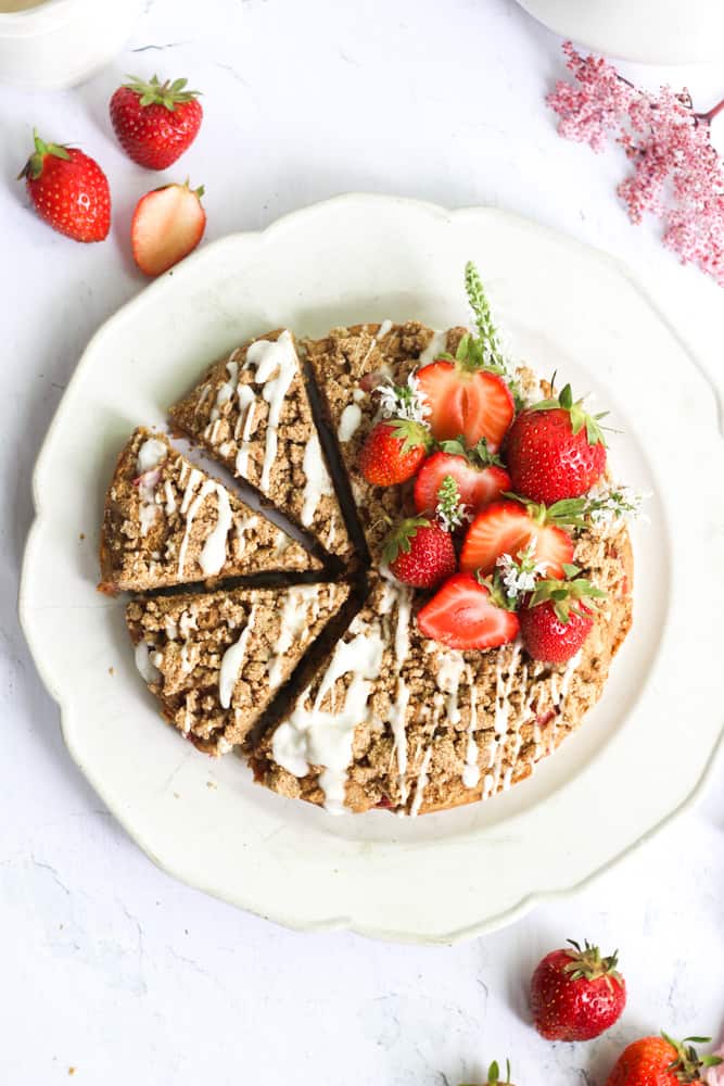 healthy strawberry banana cake with a crumble cut into 3 pieces on a white platter.