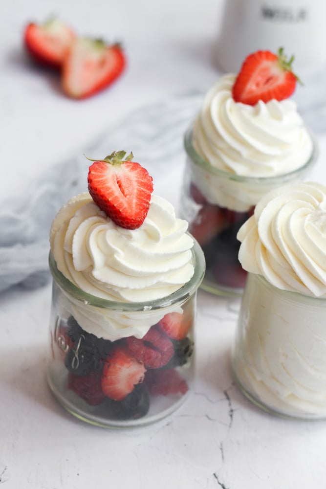 healthy whipped cream piped in a glass jar of berries.