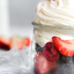 sugar free whipped cream piped onto a glass jar of fresh cut berries.