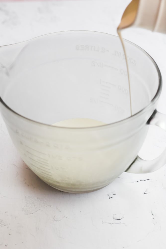 heavy cream being poured into a clear glass bowl.