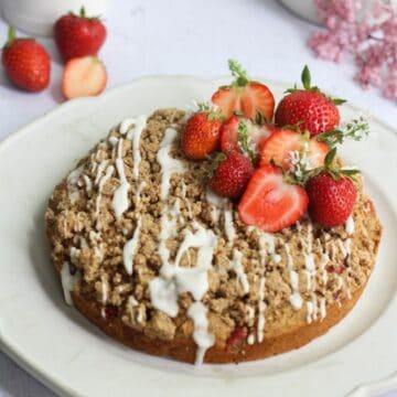 strawberry banana cake with icing drizzled on top and fresh strawberries.