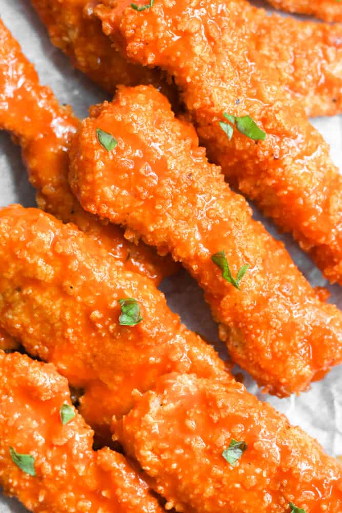 crispy air fryer chicken coated in buffalo sauce and topped with herbs.
