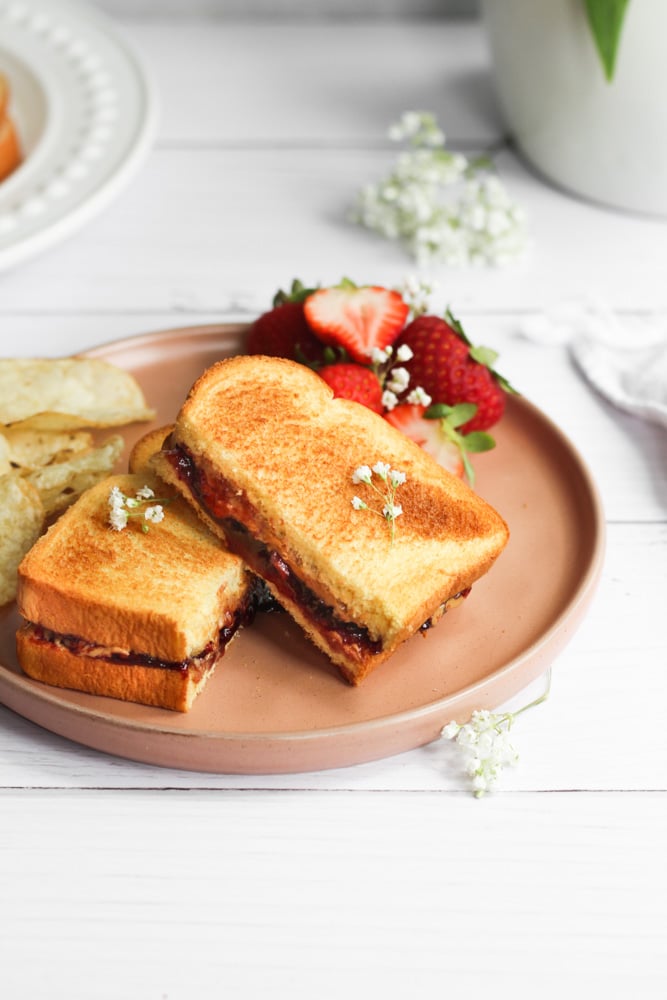 grilled pb&j on a pink plate with flowers and strawberries.