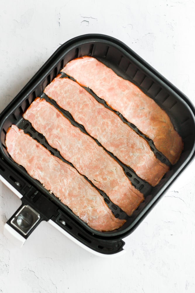 turkey bacon slices in air fryer basket.