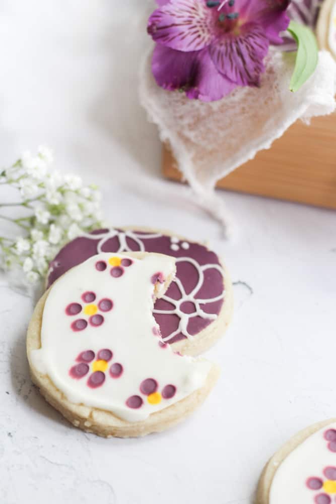 cut out cookie decorated with flowers with a bite taken.