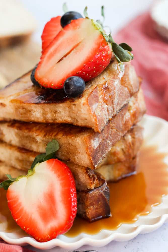 French toast on a plate with berries and syrup.