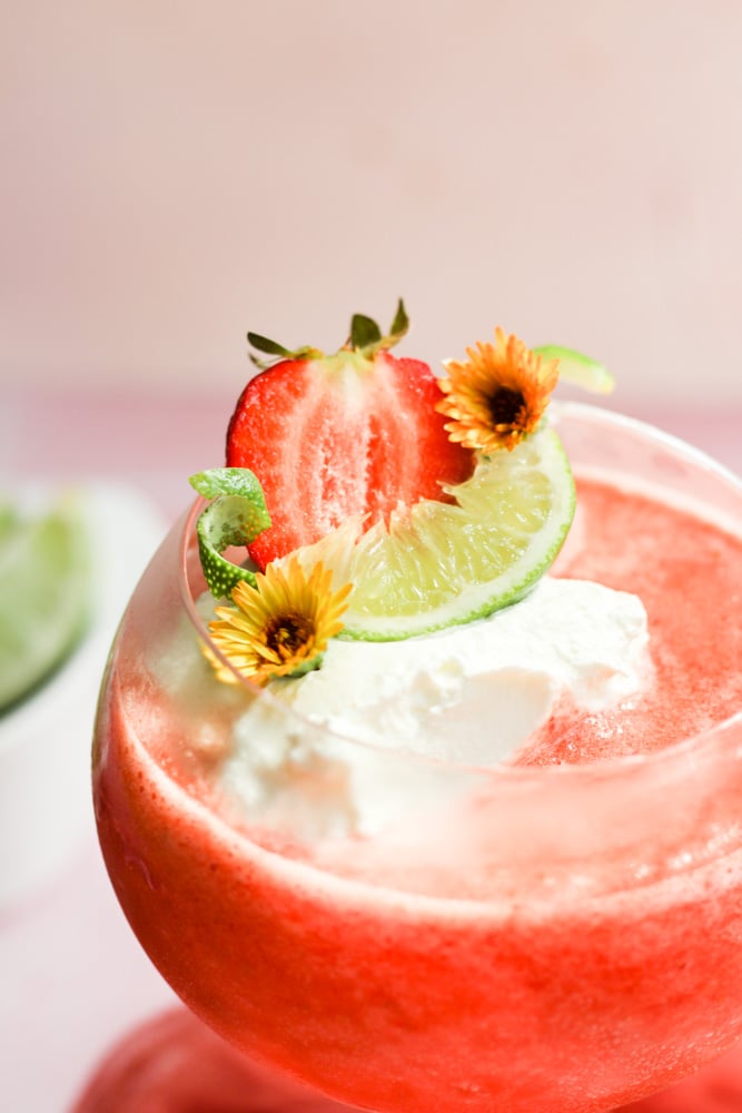 sliced strawberry, lime wedge, and whipped cream on a virgin daiquiri.
