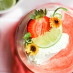 strawberry daiquiri mocktail with whipped cream, strawberry, and lime wedge.