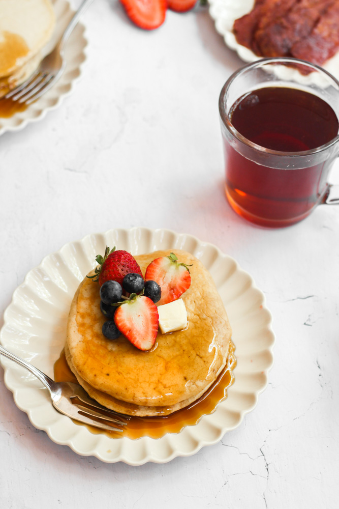 sugar free pancake recipe pancakes on a white plate with berries and maple syrup.