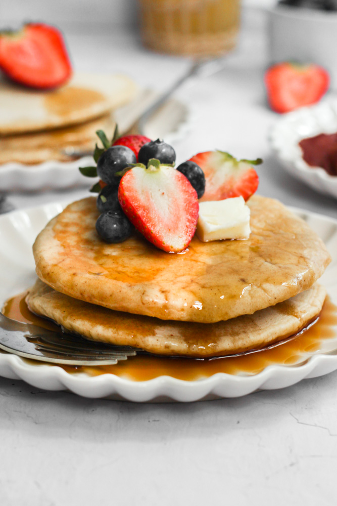 sugar free pancake recipe on a white plate topped with strawberries and syrup.