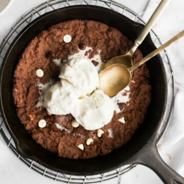 mini skillet cookie with ice cream and two gold spoons.