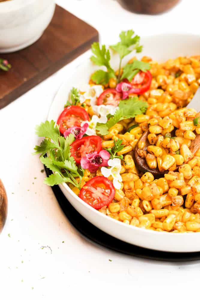 air fryer corn kernels with flowers and cilantro in white bowl.