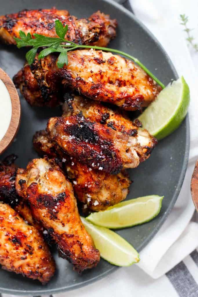 chicken wings with jerk seasoning on plate with limes.