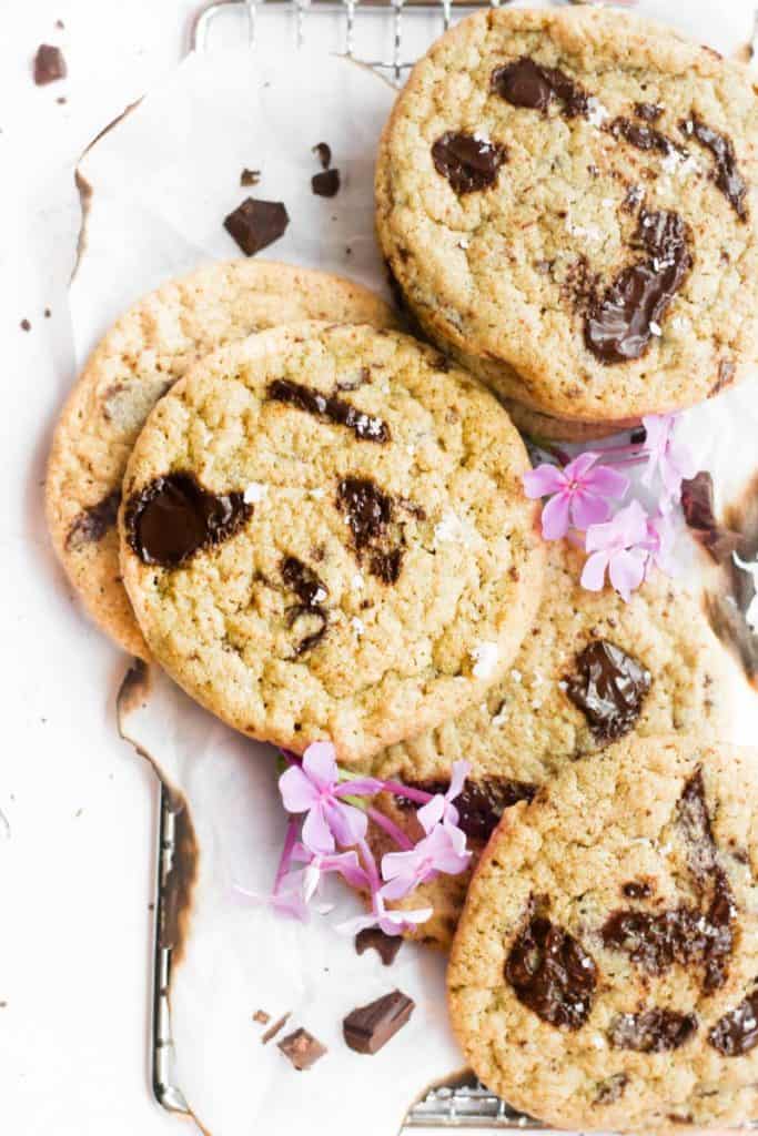 chocolate chip cookies with oat flour on parchment paper with flowers.