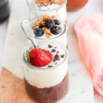 flaxseed pudding in glass jars topped with fruit and granola.