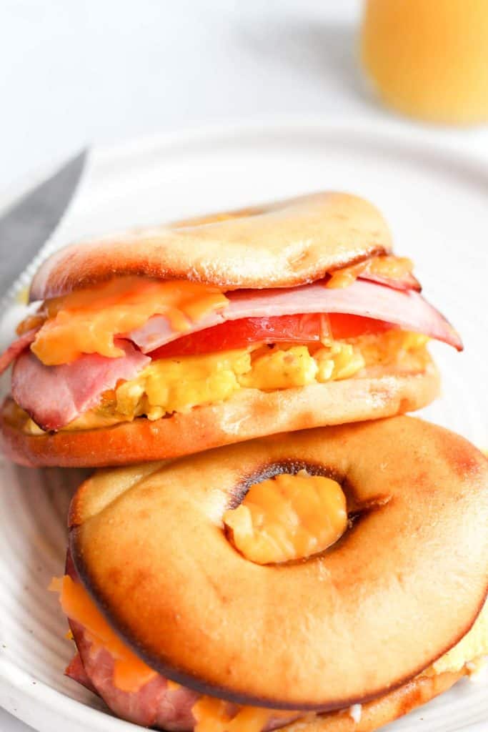 bagel sandwich with eggs, ham, tomato, and cheese.