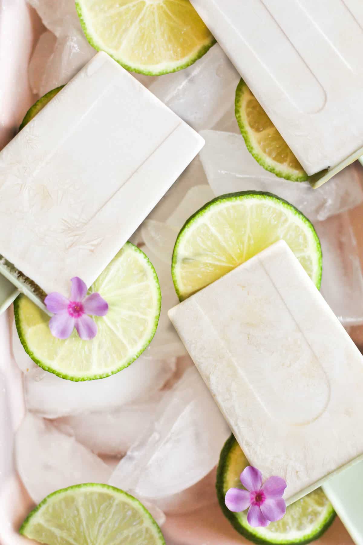 lime popsicles on a bed of ice with lime slices.