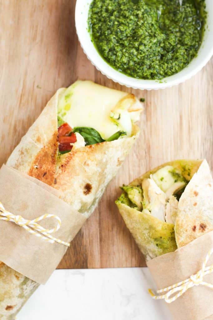 pesto chicken wraps ties with a bow on a wood board.