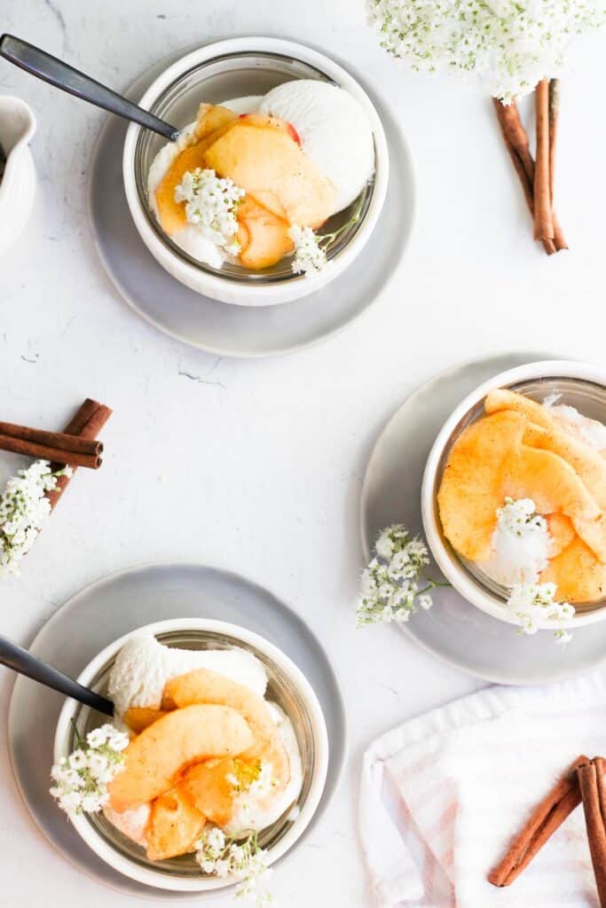 three white bowls filled with vanilla ice cream and air fryer apples.