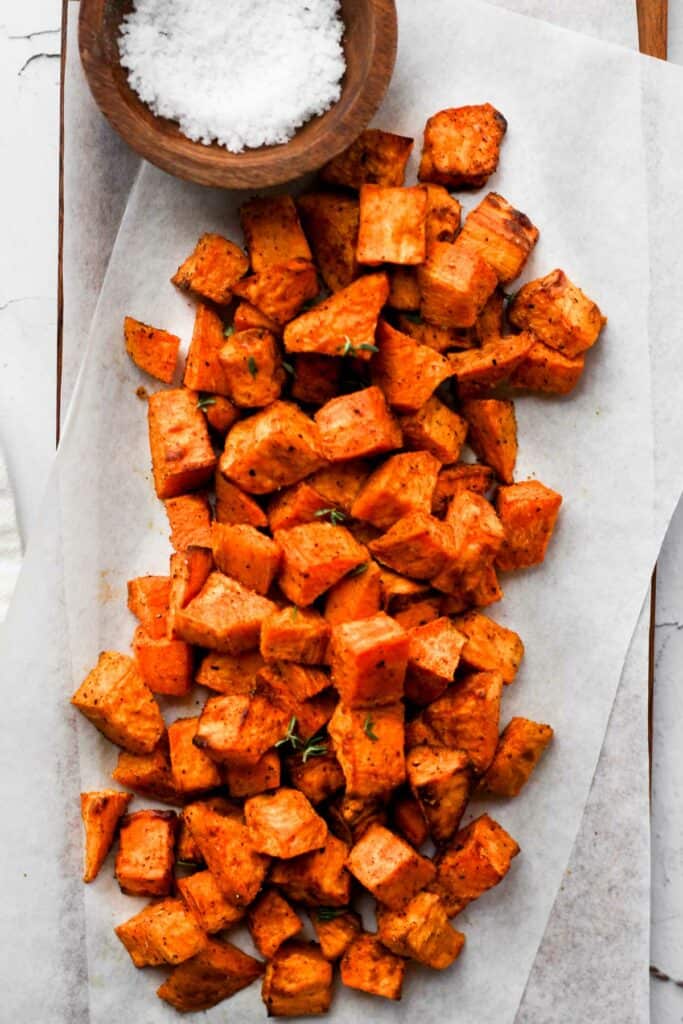 sweet potato cubes cooked in the air fryer on parchment paper with salt.
