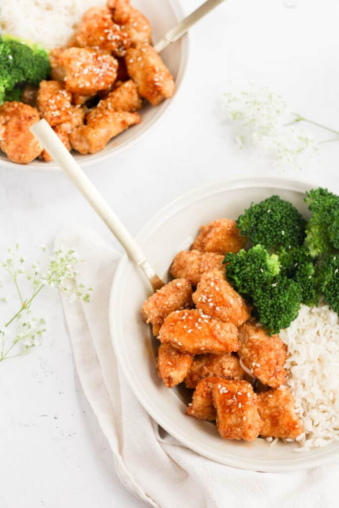 teriyaki chicken cooked in the air fryer in white bowls with rice and broccoli.