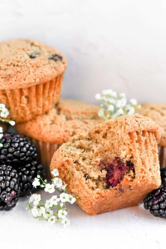 gluten free blackberry muffins piled up with a bite in one.