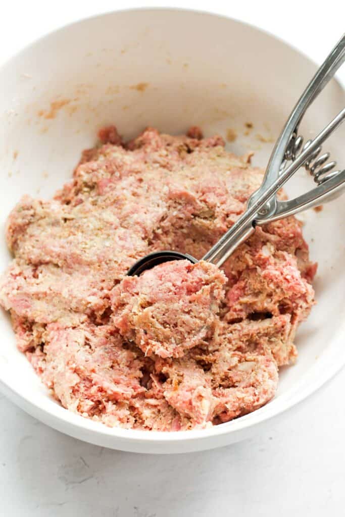 healthy meatball mixture in a white bowl with a cookie scoop.