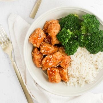 breaded air fryer teriyaki chicken topped with sesame seeds in white bowl.