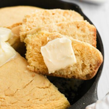 cornbread without buttermilk cut into slices with butter in cast iron pan.