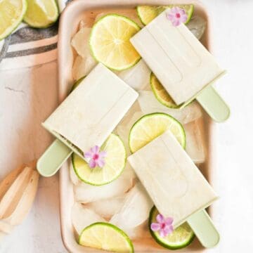 3 lime popsicles on a bed of ice with lime slices.