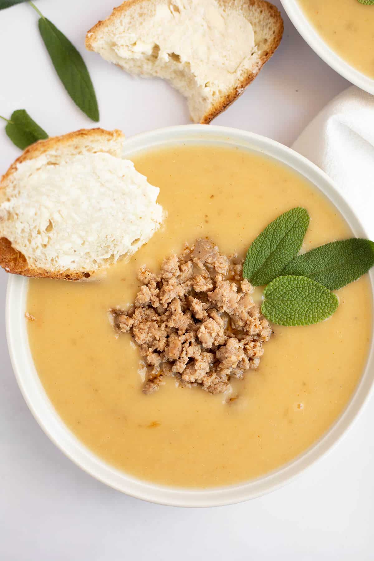 4 ingredient potato soup topped with fresh sage, sausage, and buttered bread.