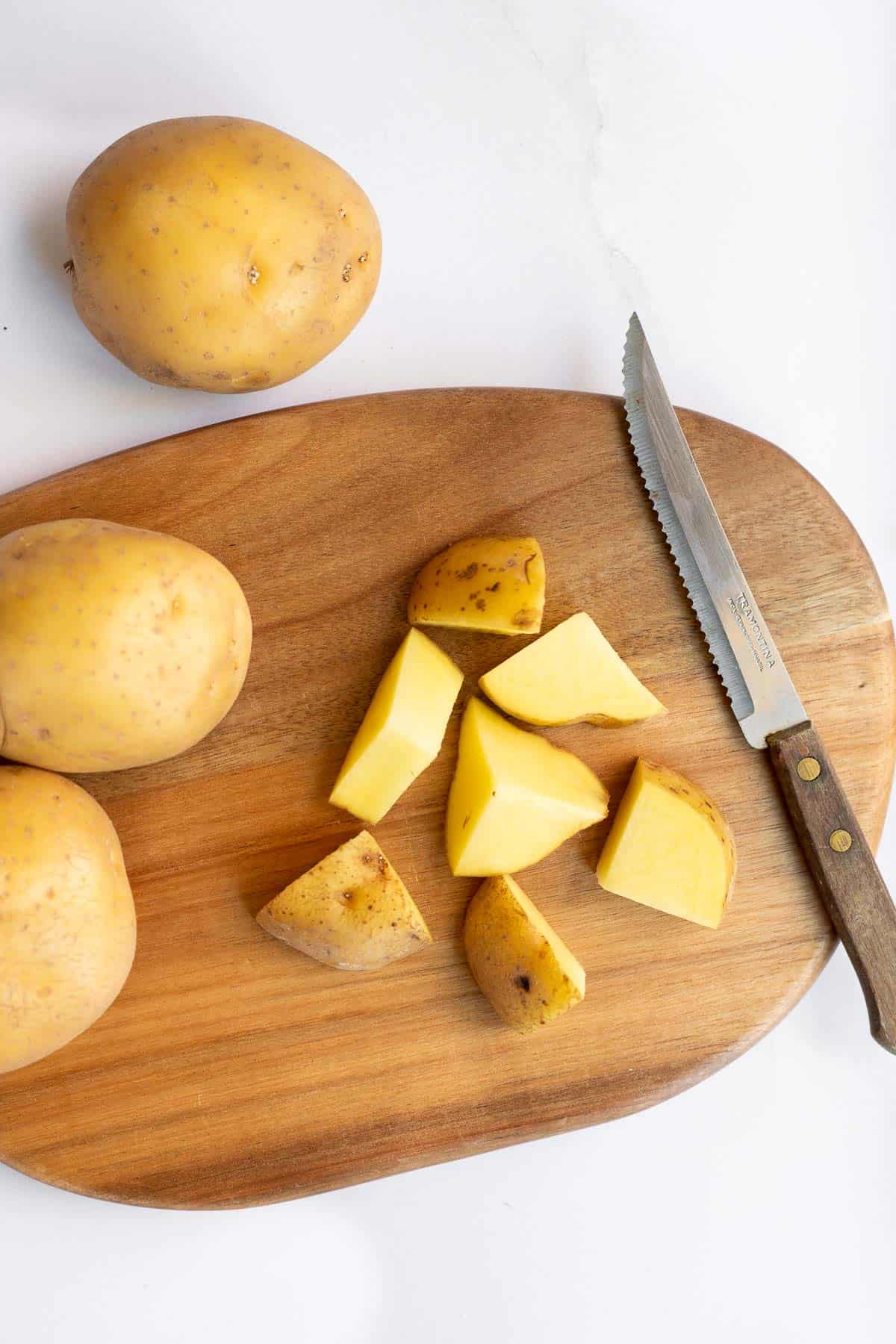 chunks of potato on wooden cutting board.