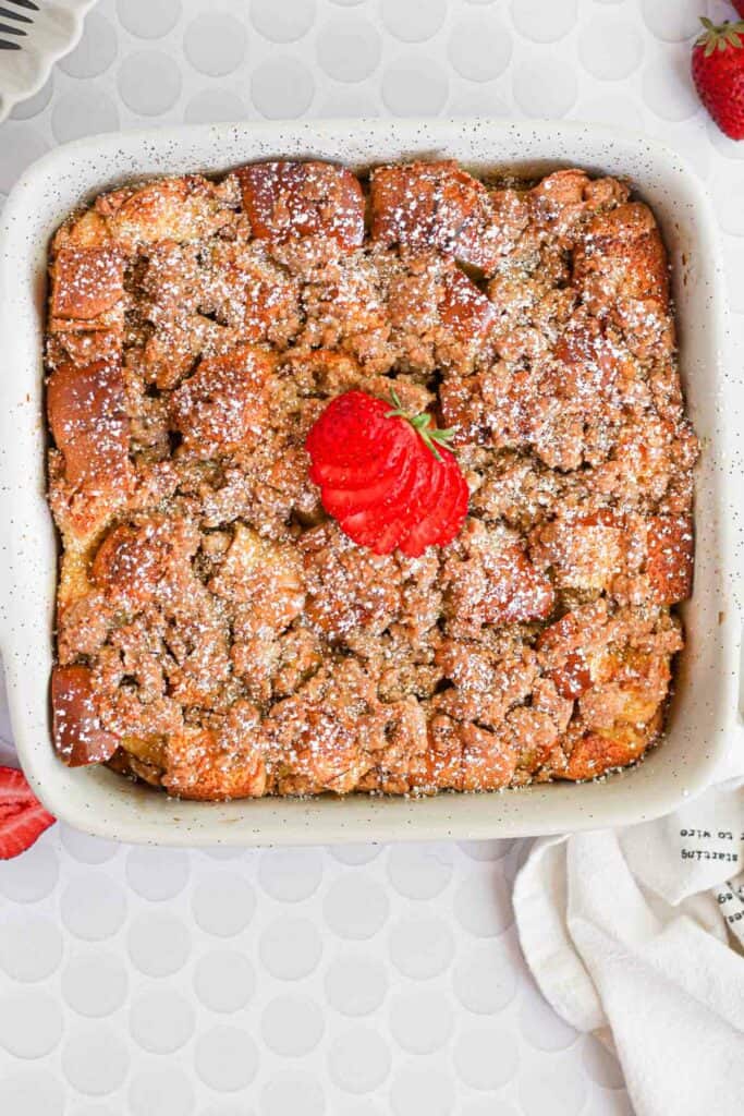 brioche french toast casserole topped with powdered sugar and strawberries.