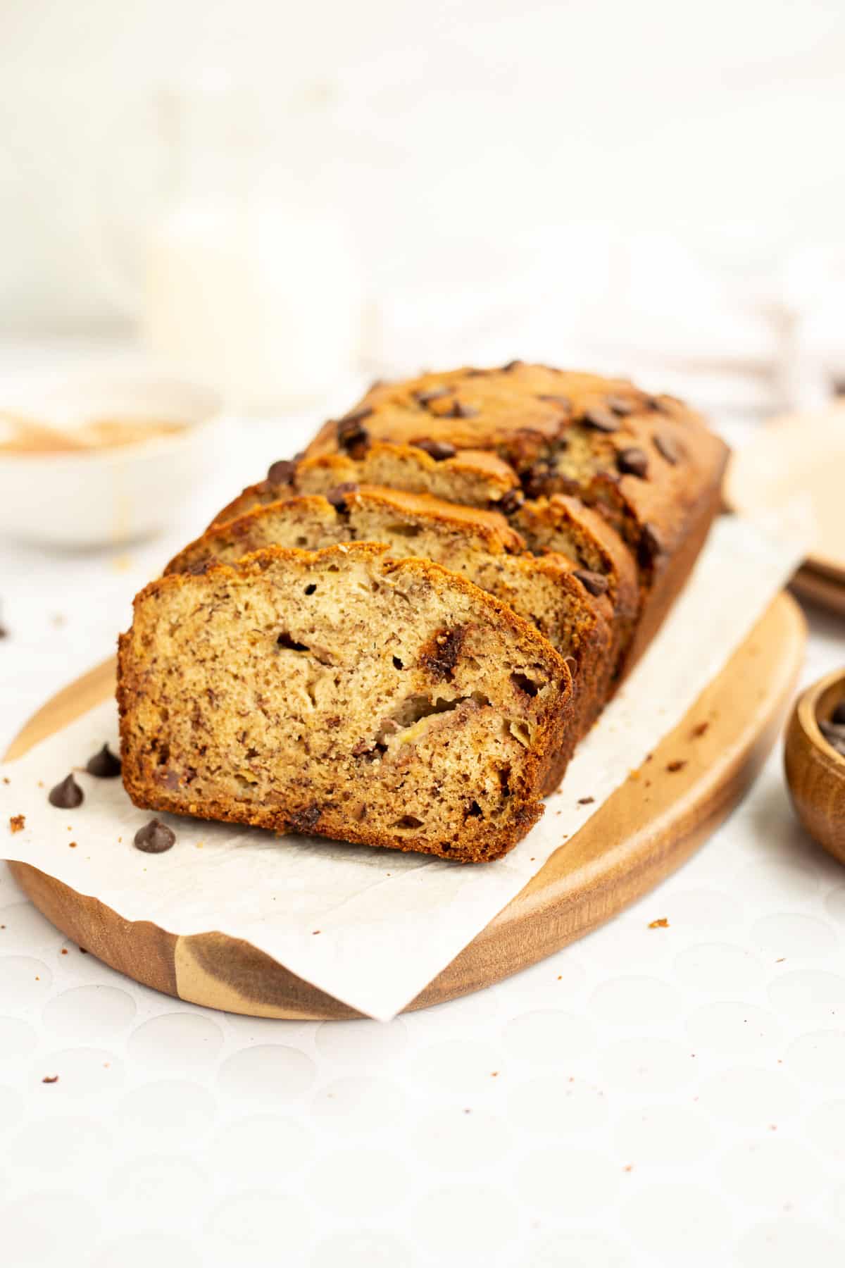 banana bread without butter with chocolate chips on wood board lined with parchment paper.