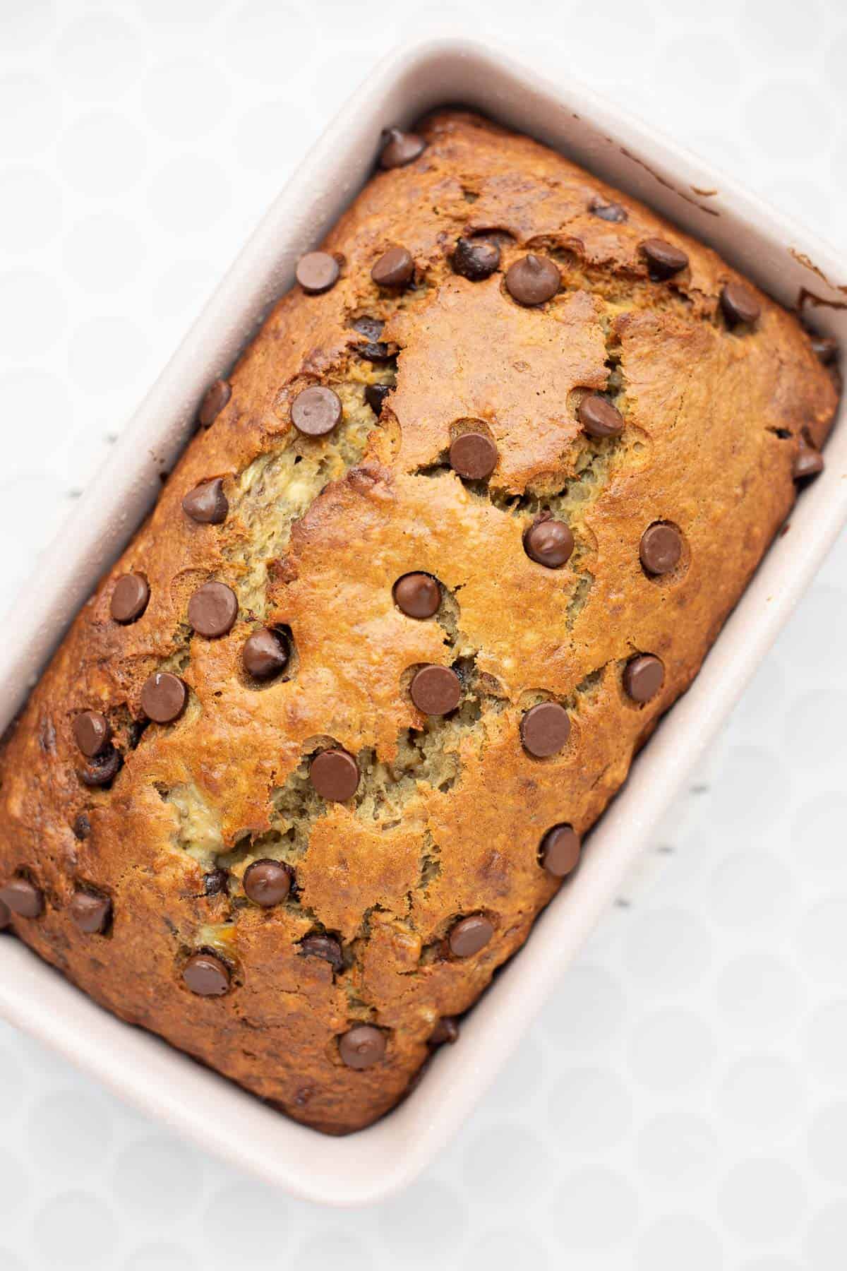 banana bread without butter baked with chocolate chips in a pink loaf pan.