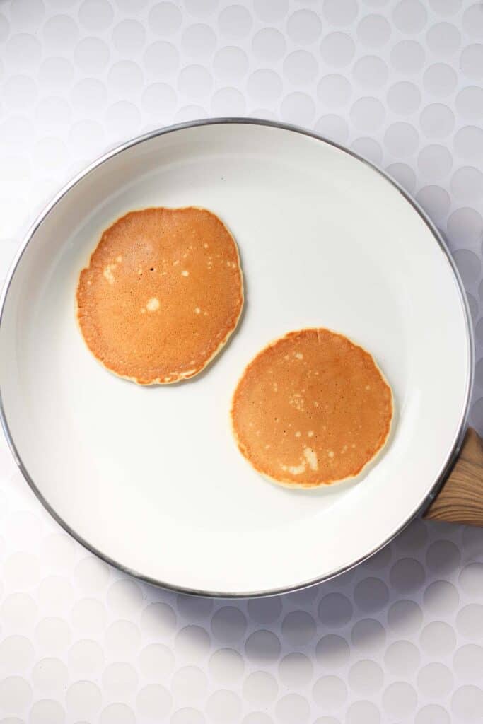 healthy pancakes with oat milk cooked in a white skillet.