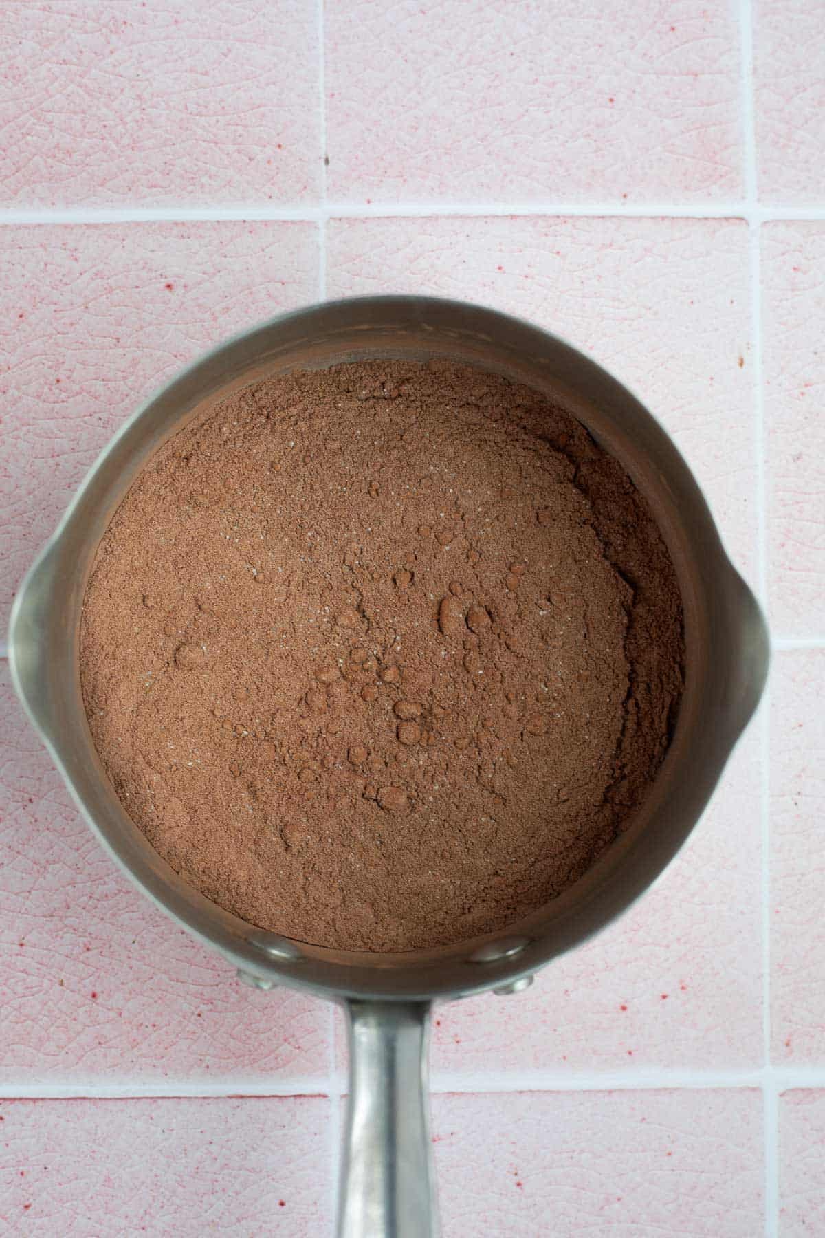 cocoa powder, protein powder, and sugar in silver pot.