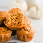 pumpkin banana muffins piled on top of each other with a bite in one.