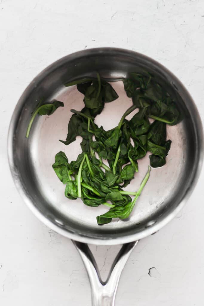 wilted spinach leaves in silver pot.
