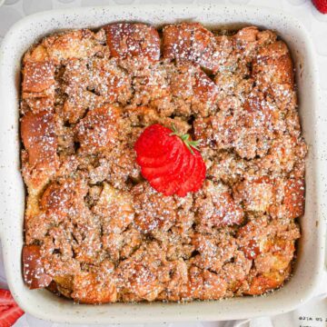 brioche french toast casserole with powdered sugar and strawberries on top.