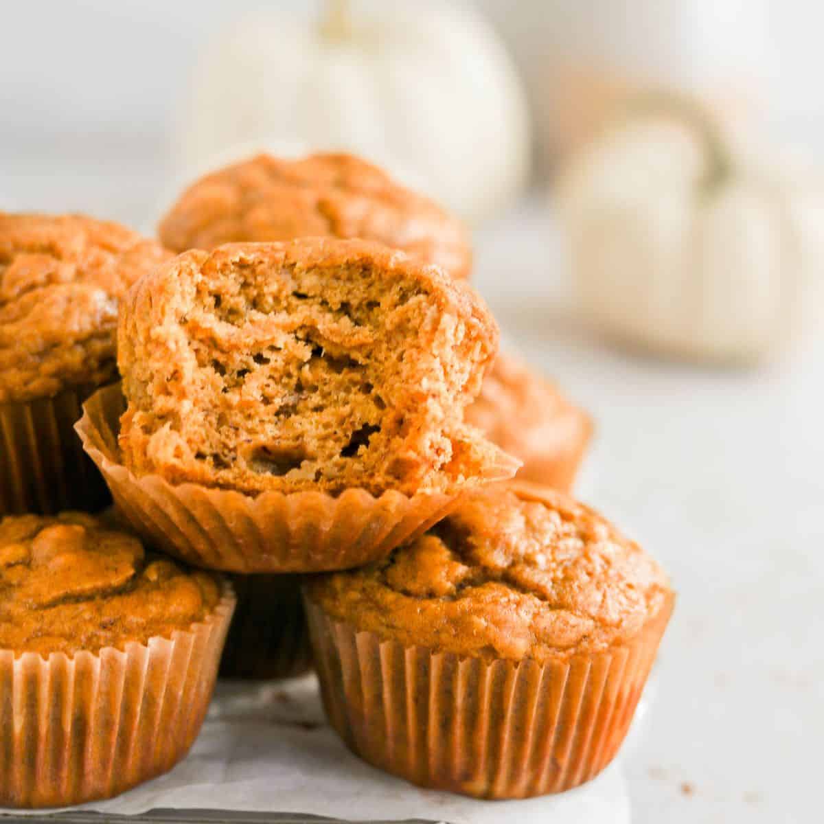 pumpkin banana muffins piled on each other with a bite in the center one.