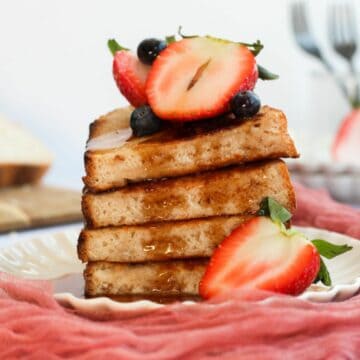 stack of sourdough french toast topped with berries and maple syrup.